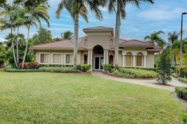 mediterranean / spanish home with stucco siding, french doors, and a front lawn
