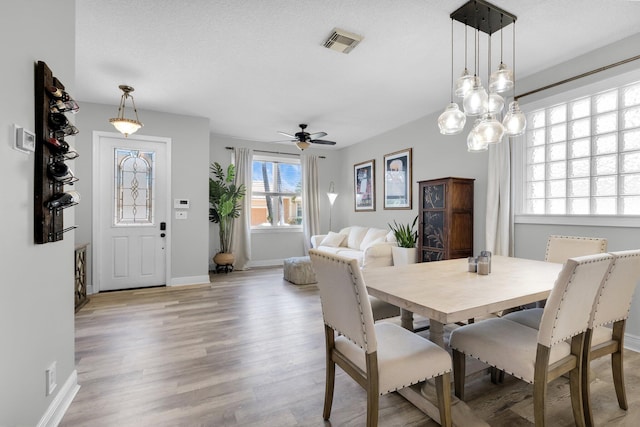 dining area with light wood-style floors, a ceiling fan, and baseboards