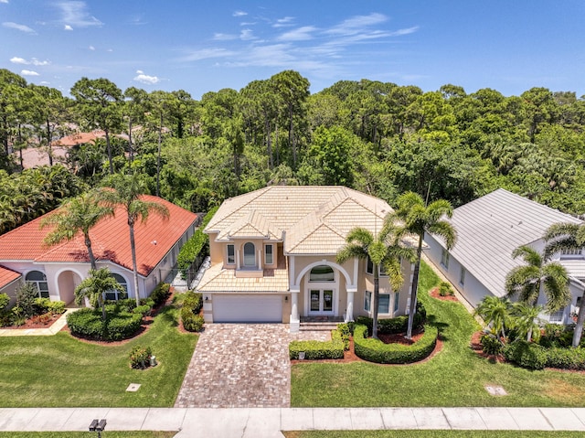 view of front facade featuring stucco siding, driveway, a tiled roof, and a front yard