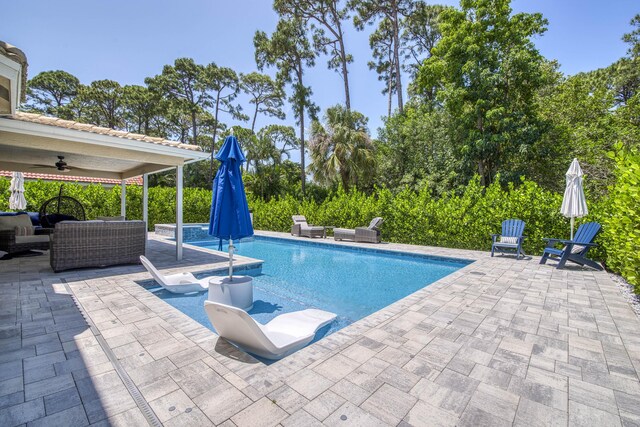 view of pool featuring a patio, ceiling fan, an outdoor living space, and a pool with connected hot tub