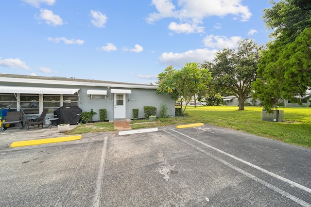 797 N Dr Unit A, Delray Beach, FL 33445 - view of front of property featuring uncovered parking, stucco siding, a front yard, and a wall unit AC