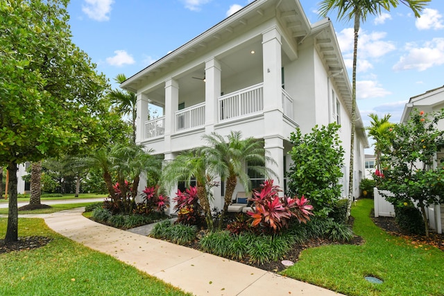 6028 Curie Pl, Palm Beach Gardens, FL 33418 - view of side of home with a balcony, a yard, and stucco siding