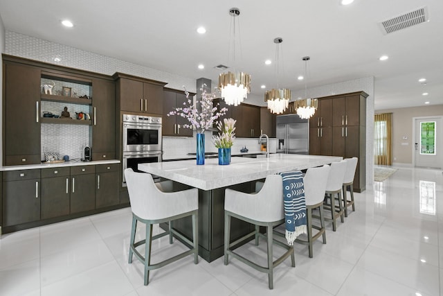 6028 Curie Pl, Palm Beach Gardens, FL 33418 - kitchen with appliances with stainless steel finishes, dark brown cabinets, a chandelier, a spacious island, and recessed lighting