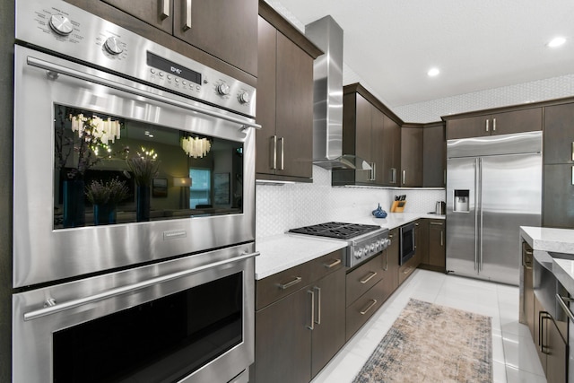 6028 Curie Pl, Palm Beach Gardens, FL 33418 - kitchen with built in appliances, wall chimney exhaust hood, dark brown cabinets, backsplash, and light tile patterned floors
