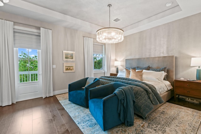 6028 Curie Pl, Palm Beach Gardens, FL 33418 - bedroom with wood-type flooring, a chandelier, a tray ceiling, and baseboards