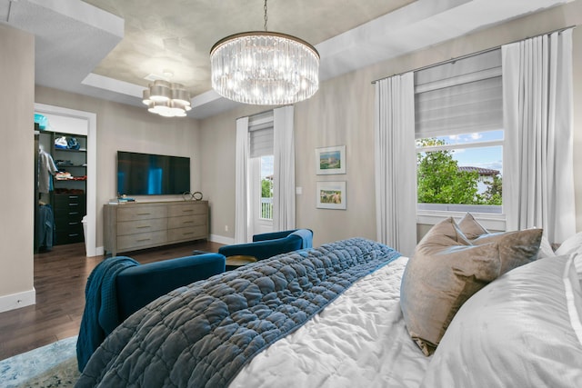 6028 Curie Pl, Palm Beach Gardens, FL 33418 - bedroom with a raised ceiling, a chandelier, wood finished floors, and baseboards