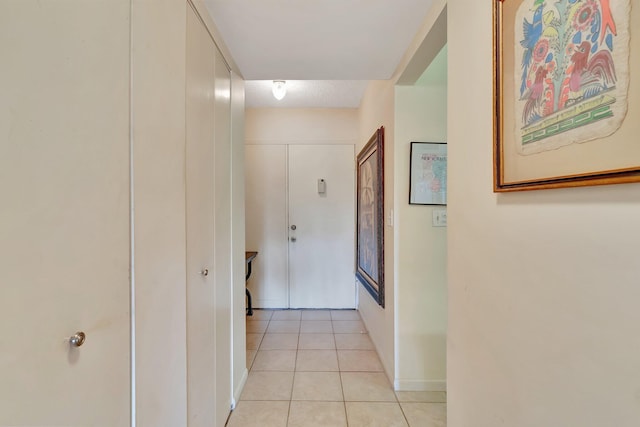 hall featuring light tile patterned floors and baseboards