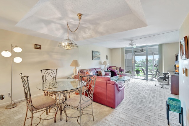 dining area featuring light colored carpet, a textured ceiling, ceiling fan, a tray ceiling, and baseboards