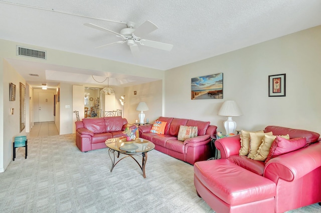 carpeted living area featuring a ceiling fan, a chandelier, and a textured ceiling