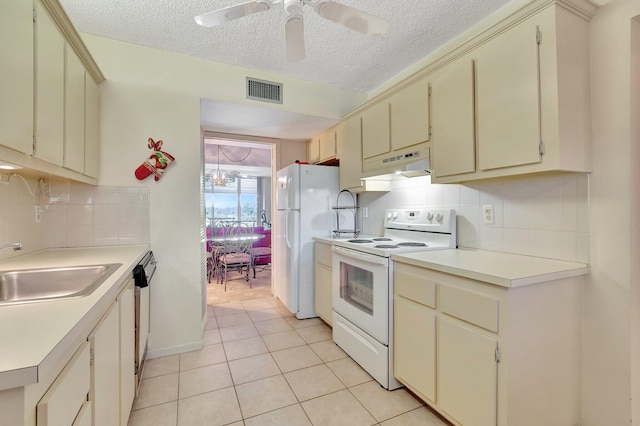 kitchen with white appliances, under cabinet range hood, a sink, cream cabinets, and ceiling fan
