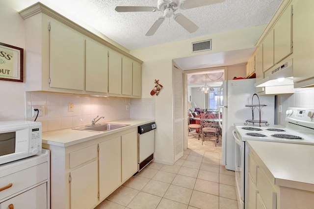 kitchen featuring white appliances, under cabinet range hood, a sink, a textured ceiling, and light countertops