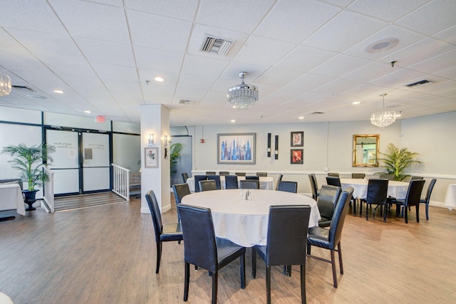 dining area featuring light wood-style floors, a chandelier, a drop ceiling, recessed lighting, and baseboards