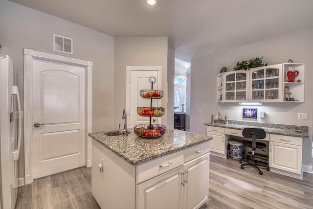2720 SE Kern Rd, Port Saint Lucie, FL 34984 - kitchen featuring light wood-style floors, a kitchen island, a sink, stainless steel fridge with ice dispenser, and white cabinetry