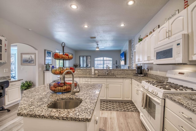 2720 SE Kern Rd, Port Saint Lucie, FL 34984 - kitchen featuring white appliances, a sink, a center island with sink, a ceiling fan, and a textured ceiling