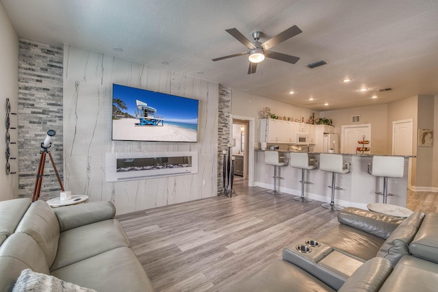 2720 SE Kern Rd, Port Saint Lucie, FL 34984 - living area featuring an accent wall, a ceiling fan, light wood finished floors, wooden walls, and recessed lighting