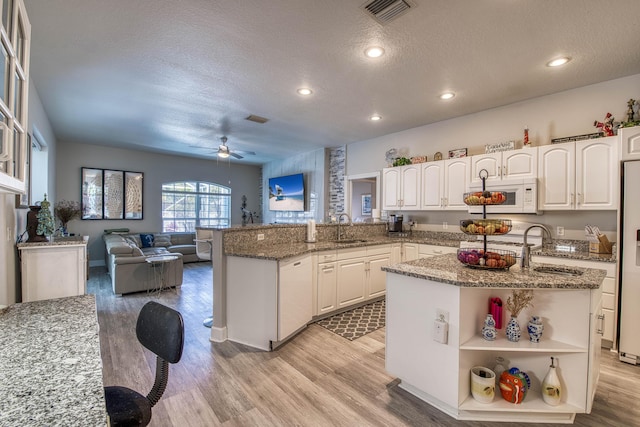 2720 SE Kern Rd, Port Saint Lucie, FL 34984 - kitchen with white microwave, a ceiling fan, a sink, a textured ceiling, and light wood finished floors