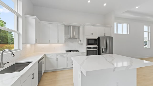 kitchen featuring wall chimney exhaust hood, stainless steel appliances, a sink, decorative backsplash, and recessed lighting