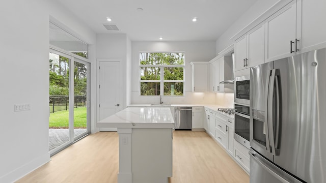 kitchen with stainless steel appliances, a center island, a sink, light wood-style flooring, and recessed lighting