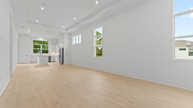 unfurnished living room featuring light wood-style flooring, healthy amount of natural light, baseboards, and recessed lighting