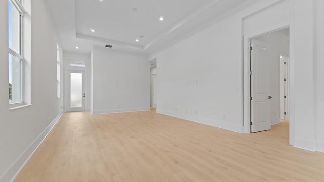 unfurnished living room featuring light wood finished floors, recessed lighting, baseboards, and a tray ceiling