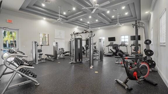exercise room with ceiling fan, beam ceiling, coffered ceiling, a towering ceiling, and ornamental molding