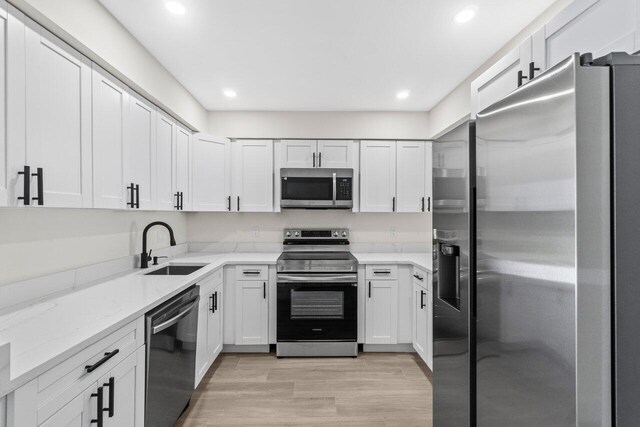 4498 NW 2nd Ave, Boca Raton, FL 33431 - kitchen featuring stainless steel appliances, a sink, light stone countertops, light wood finished floors, and white cabinets