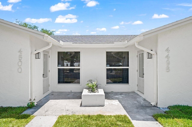 4498 NW 2nd Ave, Boca Raton, FL 33431 - doorway to property with stucco siding, a patio, and roof with shingles