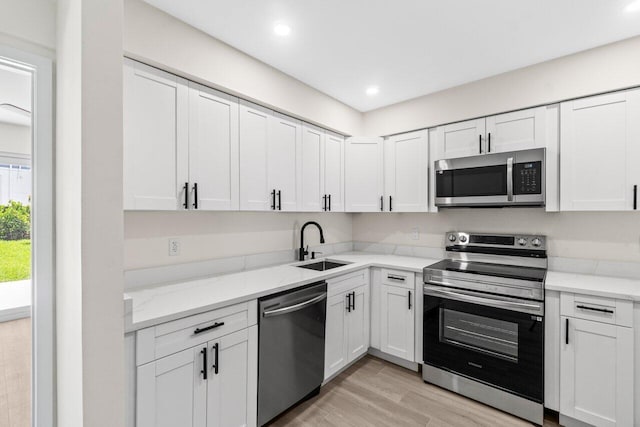 4498 NW 2nd Ave, Boca Raton, FL 33431 - kitchen featuring appliances with stainless steel finishes, a sink, light wood finished floors, white cabinetry, and light stone counters