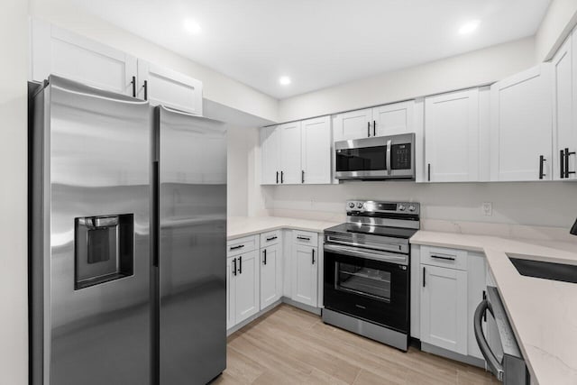 4498 NW 2nd Ave, Boca Raton, FL 33431 - kitchen with stainless steel appliances, light stone countertops, white cabinetry, light wood-style floors, and recessed lighting