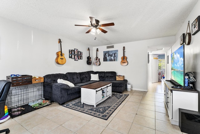 living room with a ceiling fan, a textured ceiling, light tile patterned floors, and baseboards