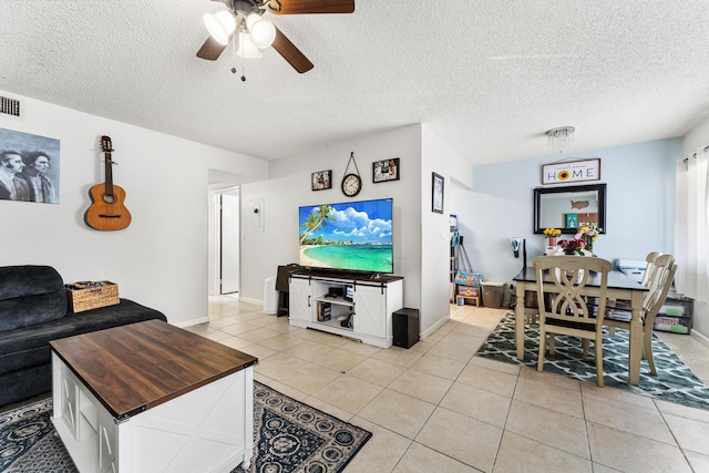 living area with a ceiling fan, light tile patterned floors, a textured ceiling, and baseboards