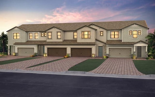 view of front facade with an attached garage, driveway, and stucco siding