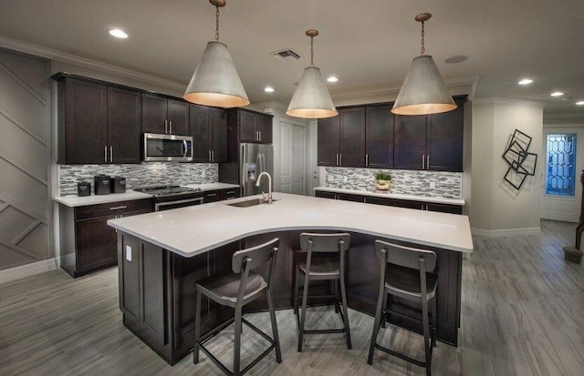 kitchen with appliances with stainless steel finishes, a sink, backsplash, crown molding, and baseboards