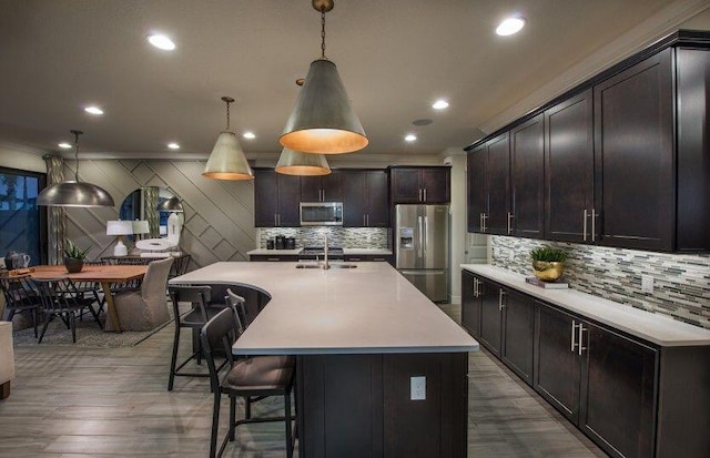kitchen with appliances with stainless steel finishes, decorative backsplash, a kitchen bar, light countertops, and a sink