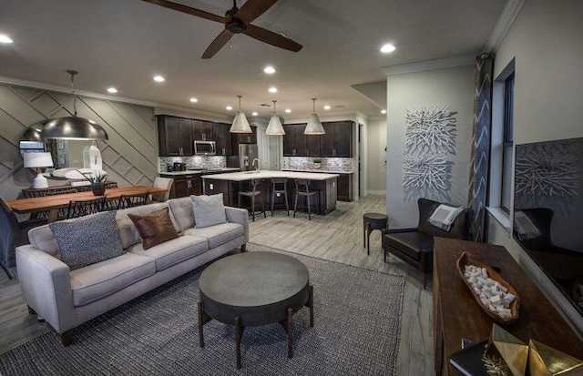 living room featuring crown molding, a ceiling fan, light wood-style floors, and recessed lighting