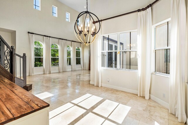 4205 Artesa Dr, Boynton Beach, FL 33436 - unfurnished dining area with a chandelier, baseboards, stairway, a towering ceiling, and marble look tiles