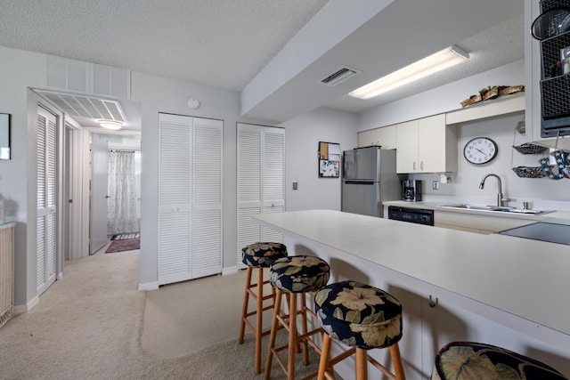 210 SE Village Dr Unit 210, Port Saint Lucie, FL 34952 - kitchen featuring freestanding refrigerator, a sink, a kitchen breakfast bar, light carpet, and light countertops