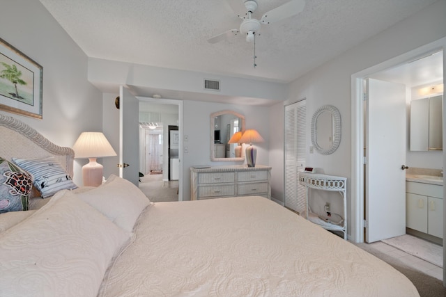 210 SE Village Dr Unit 210, Port Saint Lucie, FL 34952 - bedroom with a closet, a textured ceiling, ceiling fan, ensuite bathroom, and a sink