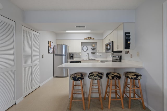 210 SE Village Dr Unit 210, Port Saint Lucie, FL 34952 - kitchen with stainless steel appliances, a sink, a peninsula, baseboards, and light countertops