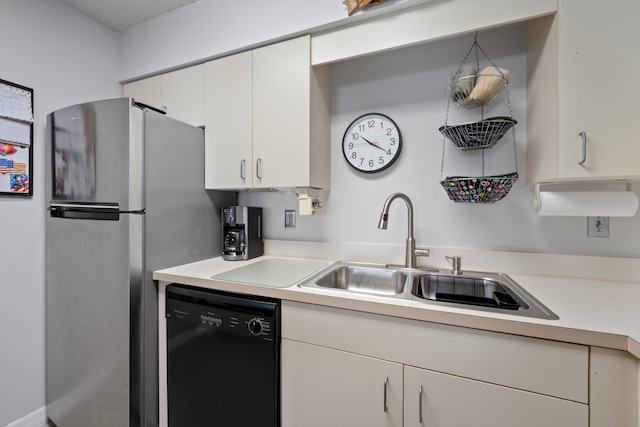 210 SE Village Dr Unit 210, Port Saint Lucie, FL 34952 - kitchen with black dishwasher, light countertops, a sink, white cabinets, and freestanding refrigerator