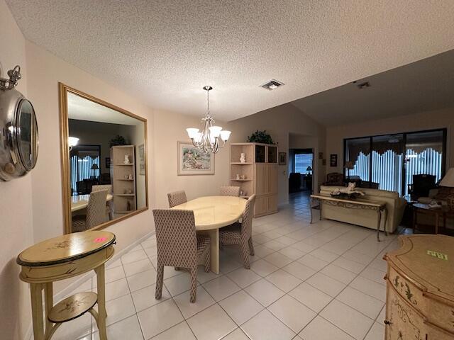 5155 Europa Dr Unit R, Boynton Beach, FL 33437 - dining space with a chandelier, a textured ceiling, light tile patterned floors, and vaulted ceiling