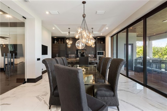 dining area featuring a tray ceiling, light marble finish flooring, a chandelier, and baseboards