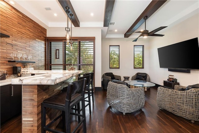 living room with beamed ceiling, wet bar, dark wood finished floors, and a ceiling fan