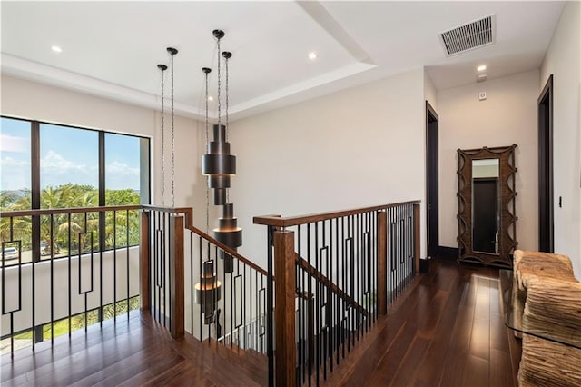 hallway featuring an upstairs landing, recessed lighting, wood finished floors, and a raised ceiling