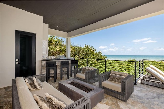 view of patio featuring an outdoor living space with a fire pit, a water view, and exterior bar