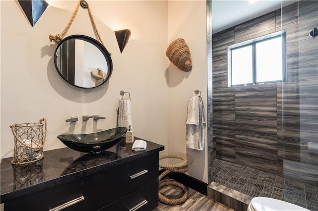 full bath featuring tiled shower, toilet, and vanity