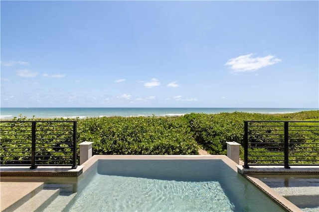 view of swimming pool featuring view of water and beach