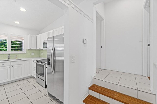 22 Pepperwood Ct, Boynton Beach, FL 33426 - kitchen with appliances with stainless steel finishes, a sink, light countertops, white cabinetry, and lofted ceiling