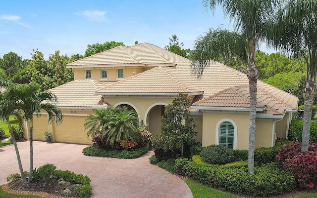 7668 SE Laque Cir, Stuart, FL 34997 - mediterranean / spanish-style home with a tiled roof, stucco siding, decorative driveway, and a garage