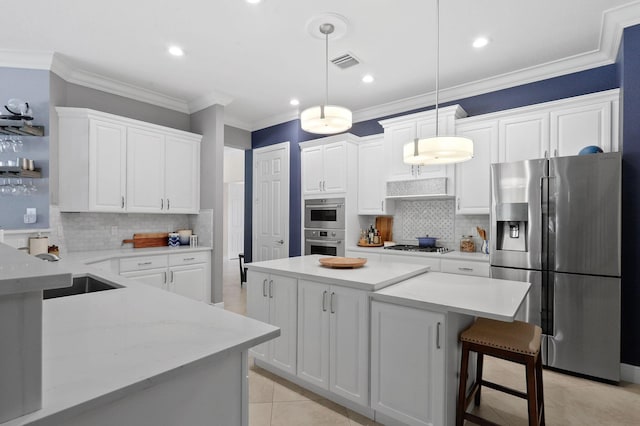 7668 SE Laque Cir, Stuart, FL 34997 - kitchen with stainless steel appliances, tasteful backsplash, white cabinets, a kitchen island, and ornamental molding